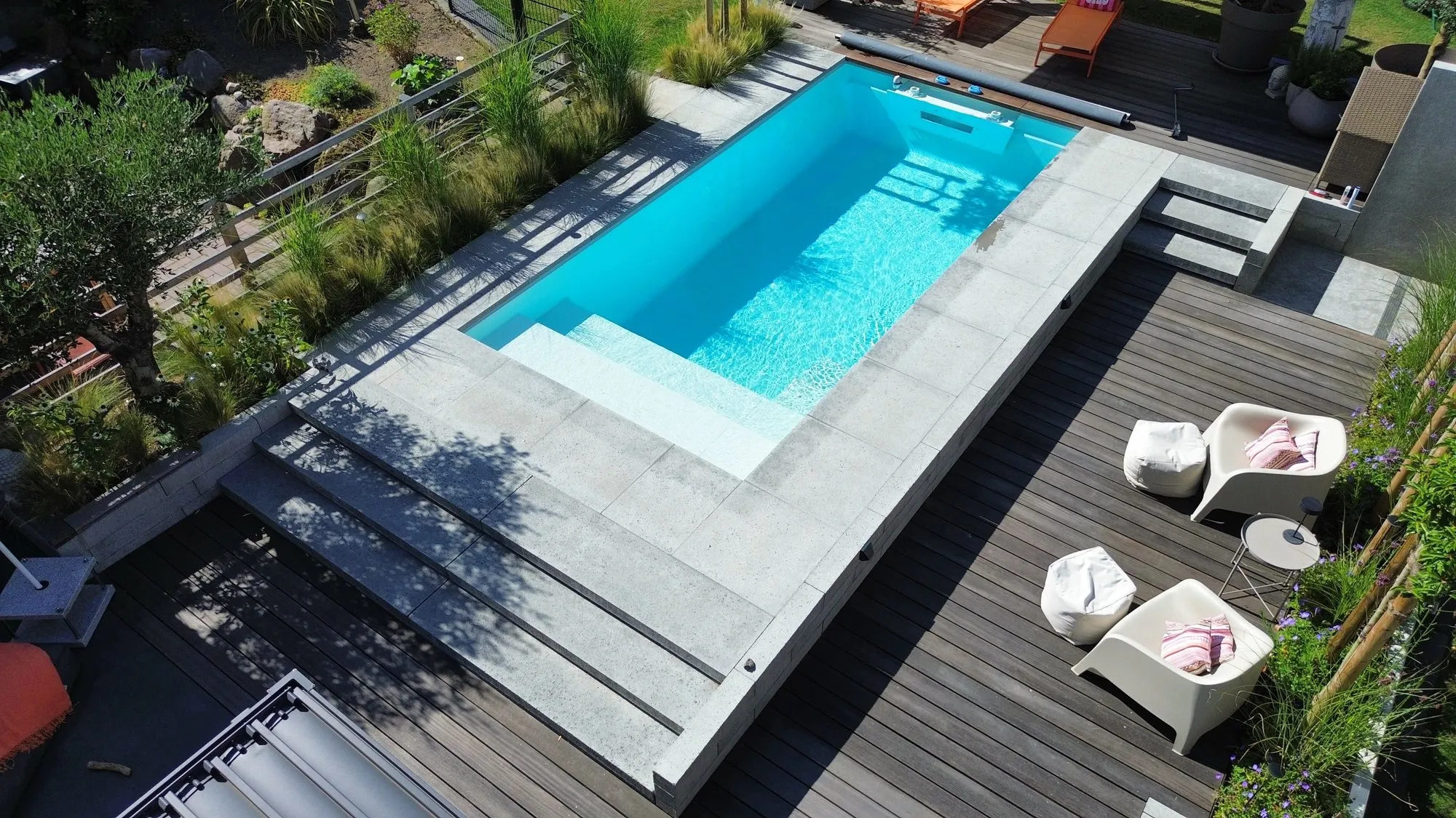 Poolgarten von oben: Unter dem Lamellendach. Deck, Dach und Becken auf einer Höhe. Der Rasen daneben bleibt Rasen.