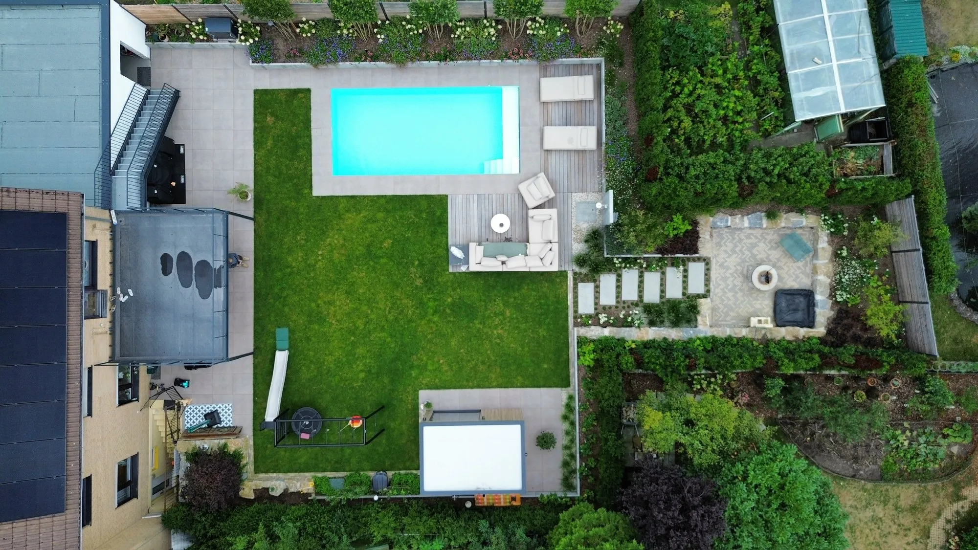Poolgarten von oben: Sitzplatz, Wasser, Gartenhaus. Lounge am Becken, Dusche daneben, Gartenhaus dahinter — und abends Licht im Beet.